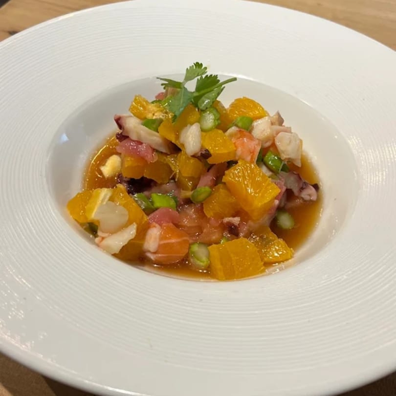 KANBU Sushi Downtown's vibrant ceviche with seafood, orange segments, and green garnish in a white bowl.