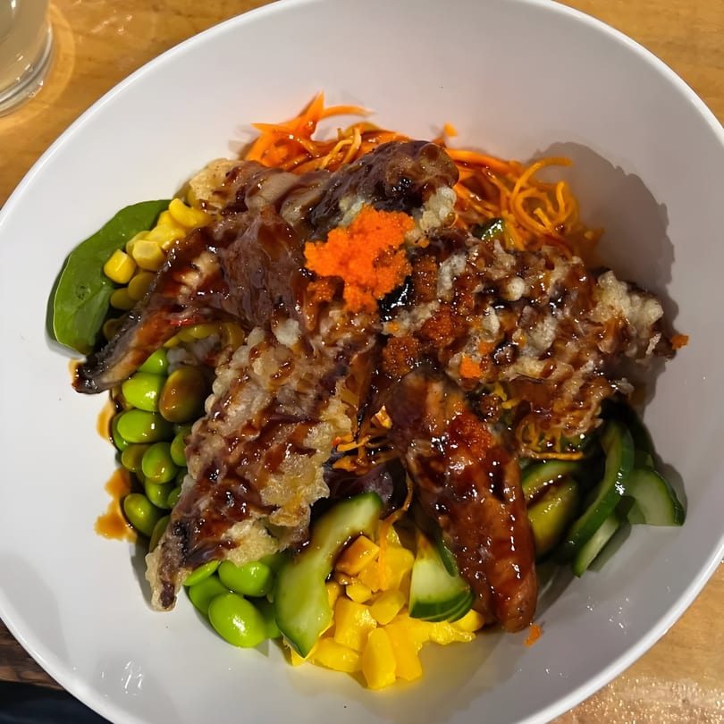 A KANBU Sushi Downtown poke bowl with tempura, edamame, corn, mango, and shredded carrots.