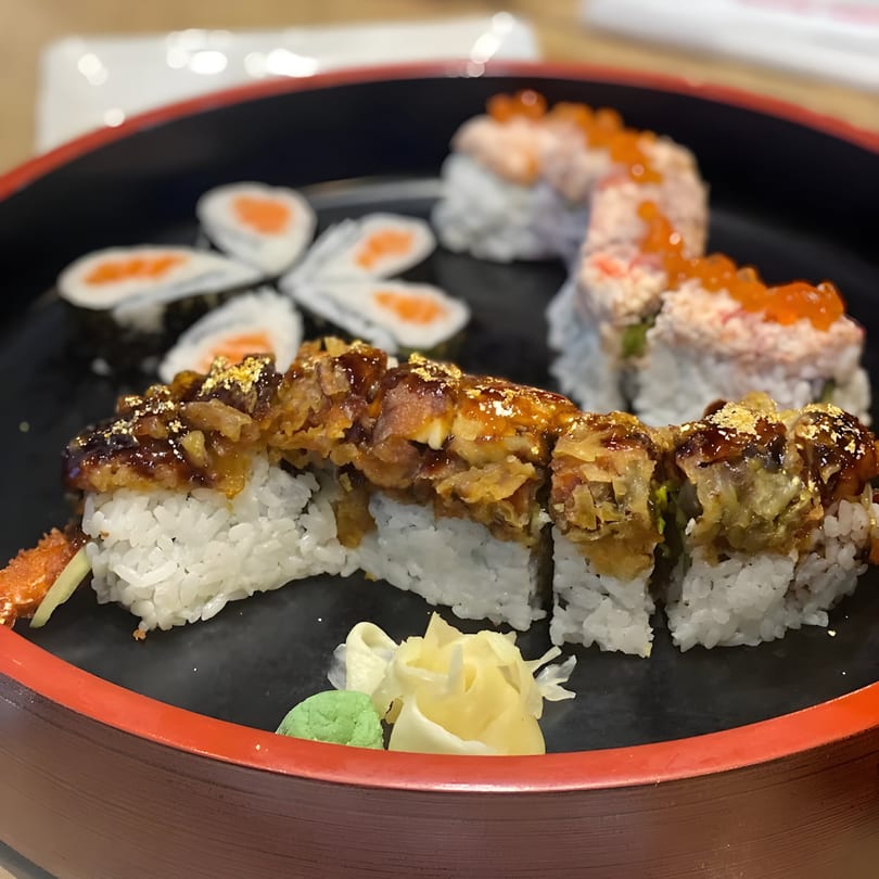 A black and red platter of KANBU Sushi Downtown's assorted sushi rolls, including a dragon roll.